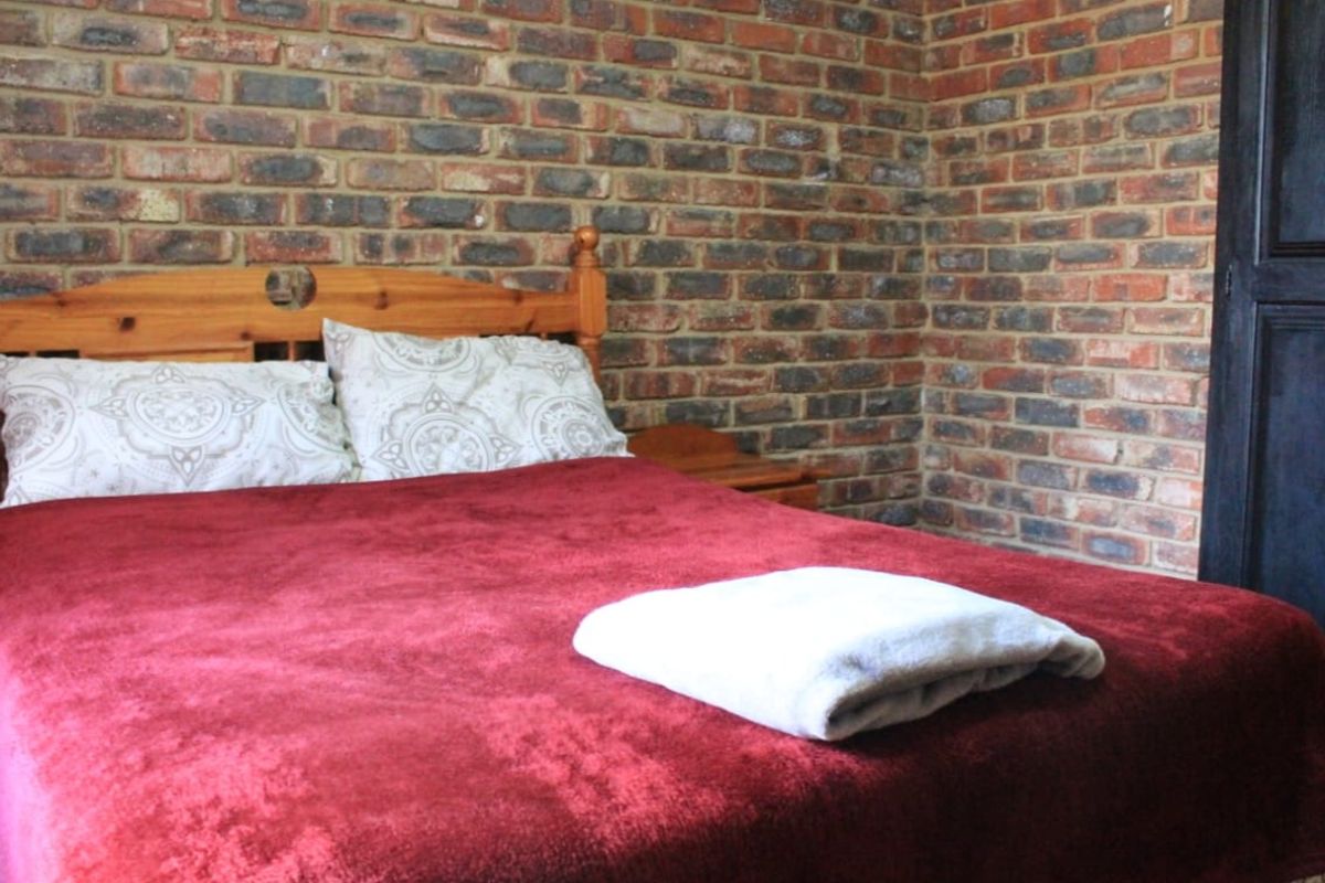 A bedroom featuring a rustic exposed face-brick feature wall and a built-in door.