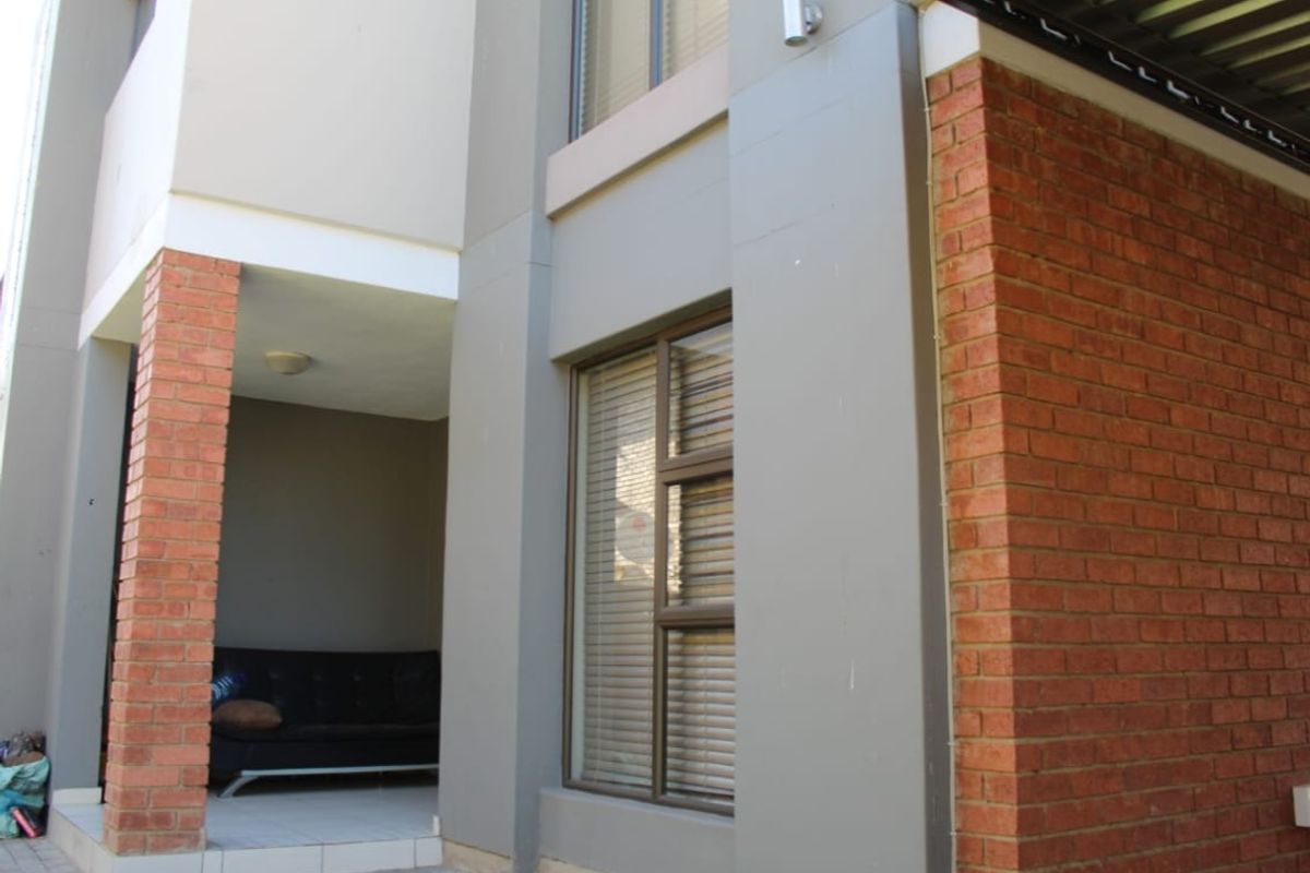 A view of the townhouse exterior featuring a combination of face brick and painted plaster finishes with aluminium window frames.