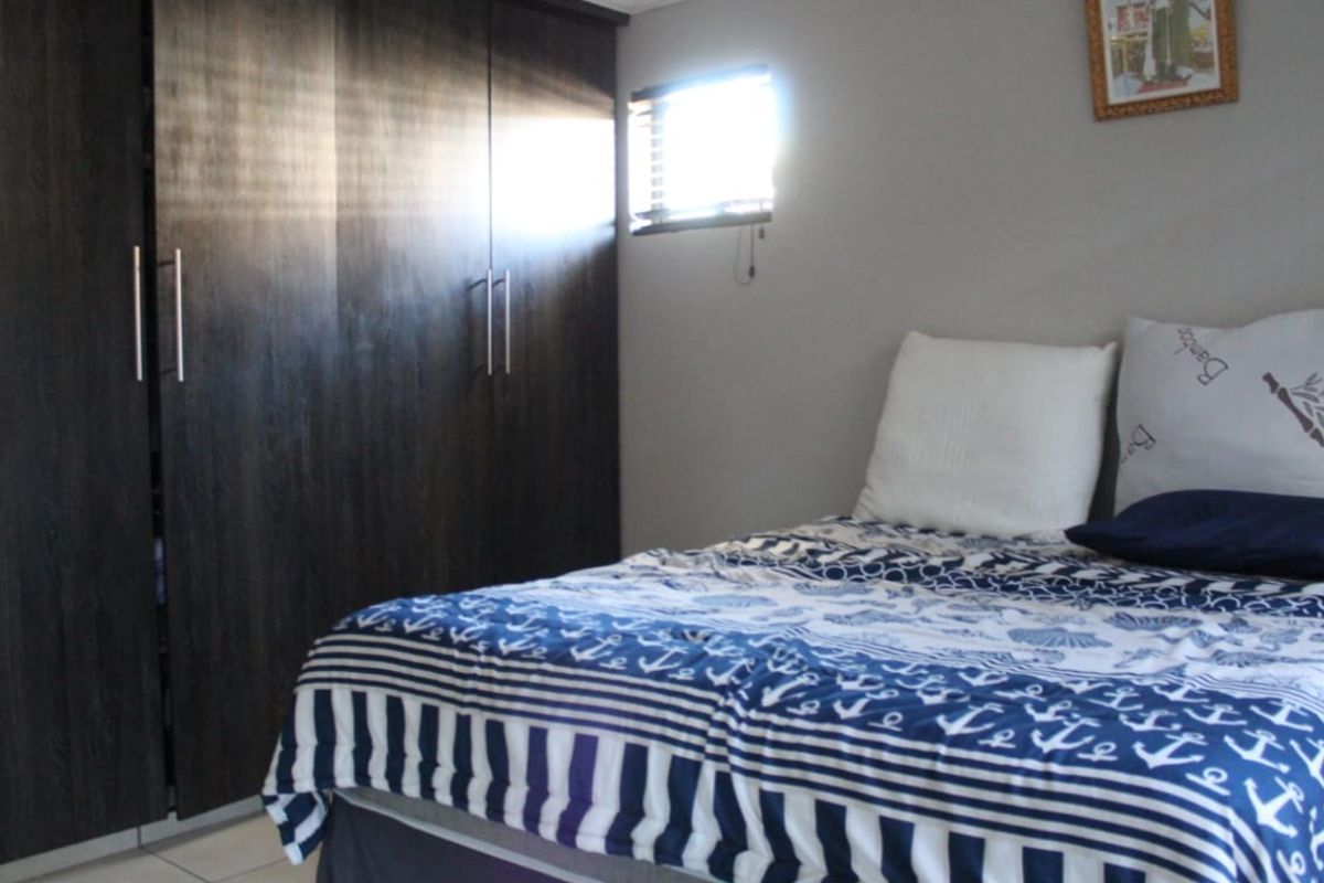 A bedroom featuring dark wood built-in cupboards and tiled flooring, providing functional storage space.