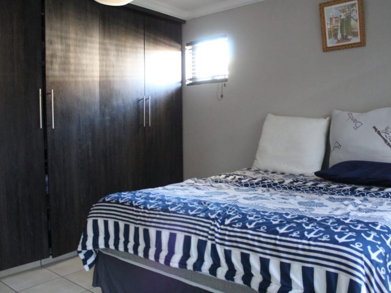 A bedroom featuring dark wood built-in cupboards and tiled flooring, providing functional storage space.