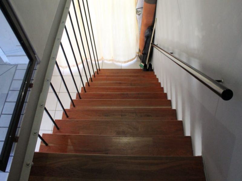 A staircase featuring wooden treads, a metal handrail, and vertical metal balustrades, providing access between levels.