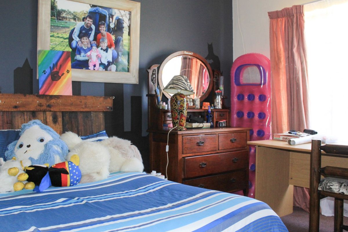 A bedroom featuring dark painted walls, carpeted flooring, and a window with curtains.