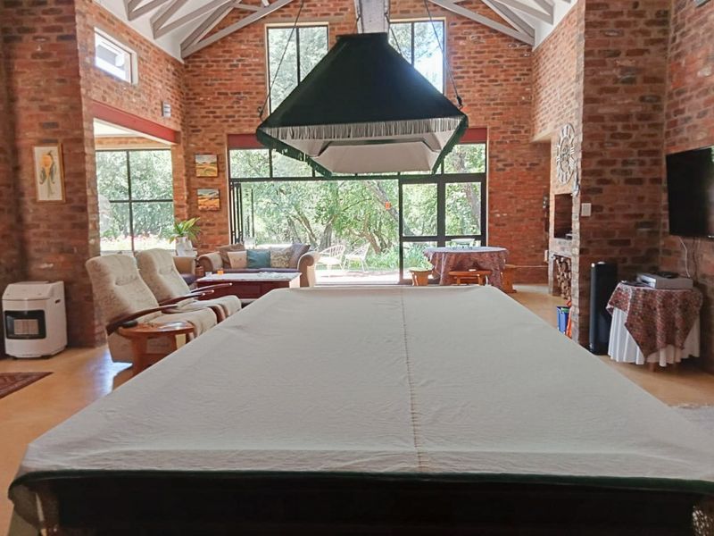 Spacious living area featuring high vaulted ceilings with exposed trusses, striking brickwork, and large glass doors opening to the garden.