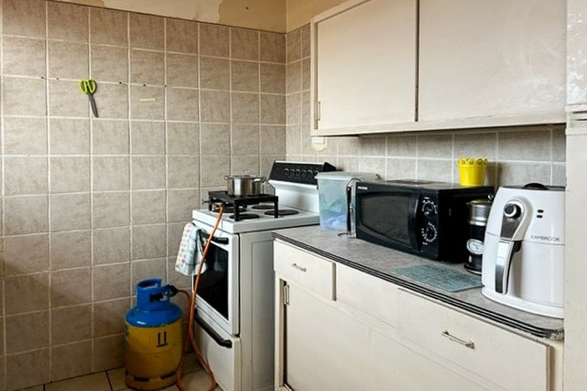 A compact kitchen featuring tiled walls, built-in cabinetry, and a gas stove setup.