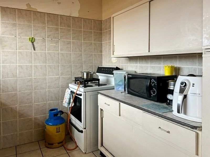 A compact kitchen featuring tiled walls, built-in cabinetry, and a gas stove setup.
