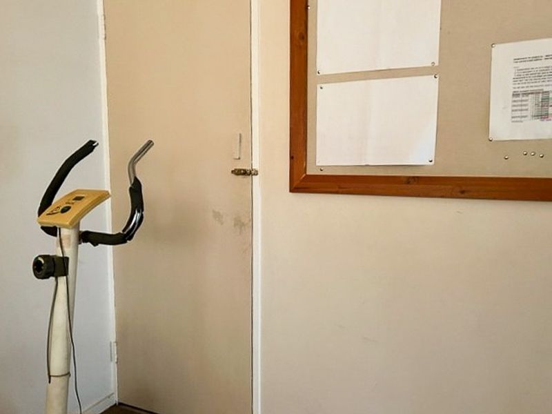 A view of an interior wall featuring a plain door and a wooden-framed notice board.