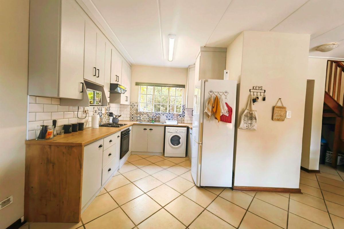 A functional kitchen featuring light-toned cabinetry, wood-look countertops, tiled backsplash, and integrated laundry appliance space.