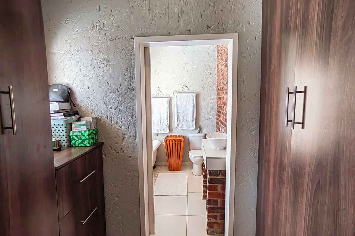 View from a bedroom area into an en-suite bathroom featuring a vessel sink, brick vanity base, and tiled flooring.