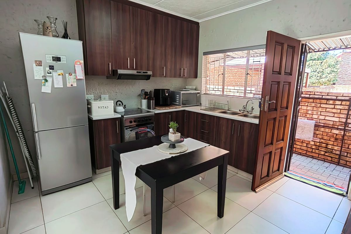 Functional kitchen featuring dark wood cabinetry, tiled flooring, and direct access to an outdoor patio area.