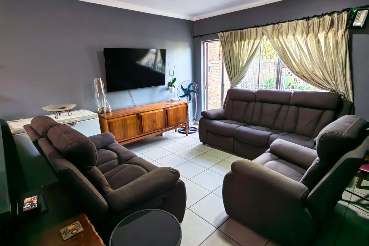 A comfortable living room featuring tiled flooring, dark grey walls, and a sliding door providing access to the exterior.