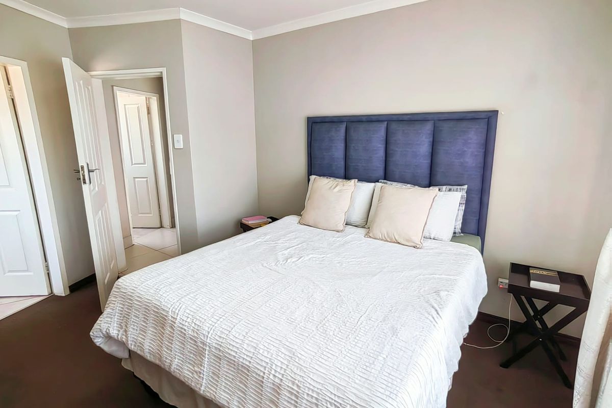 A well-maintained bedroom featuring neutral wall tones, carpeted flooring, and a classic panel door leading to an adjacent hallway.