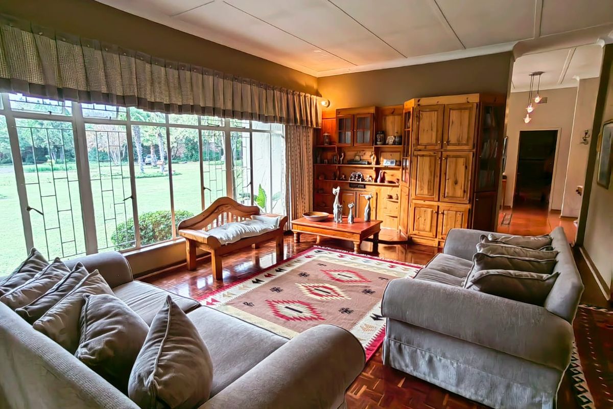 Spacious living room featuring large windows with garden views, parquet flooring, and built-in wooden cabinetry, offering a warm and inviting atmosphere.