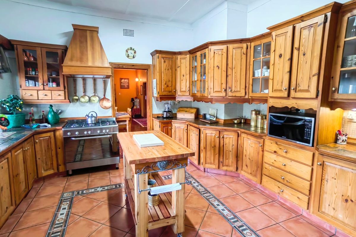 Spacious kitchen featuring extensive solid wood cabinetry, a gas stove with extractor hood, built-in microwave, and decorative tiled flooring.