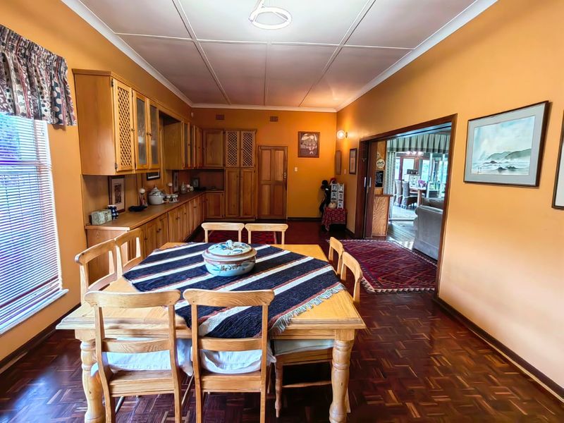 A dining room featuring traditional parquet flooring, built-in wooden cabinetry, and a sliding door leading to an adjacent living area.