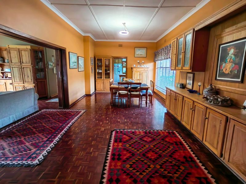Spacious dining room featuring classic parquet flooring and extensive built-in wooden cabinetry, offering a warm and traditional aesthetic.