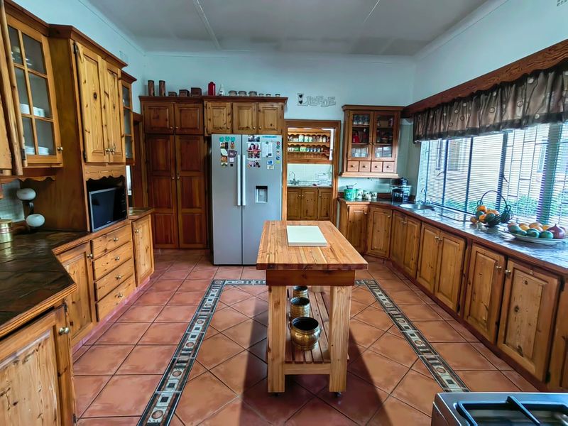 Spacious kitchen featuring extensive wooden cabinetry, tiled flooring with decorative border, and a central island, offering a traditional and functional workspace.