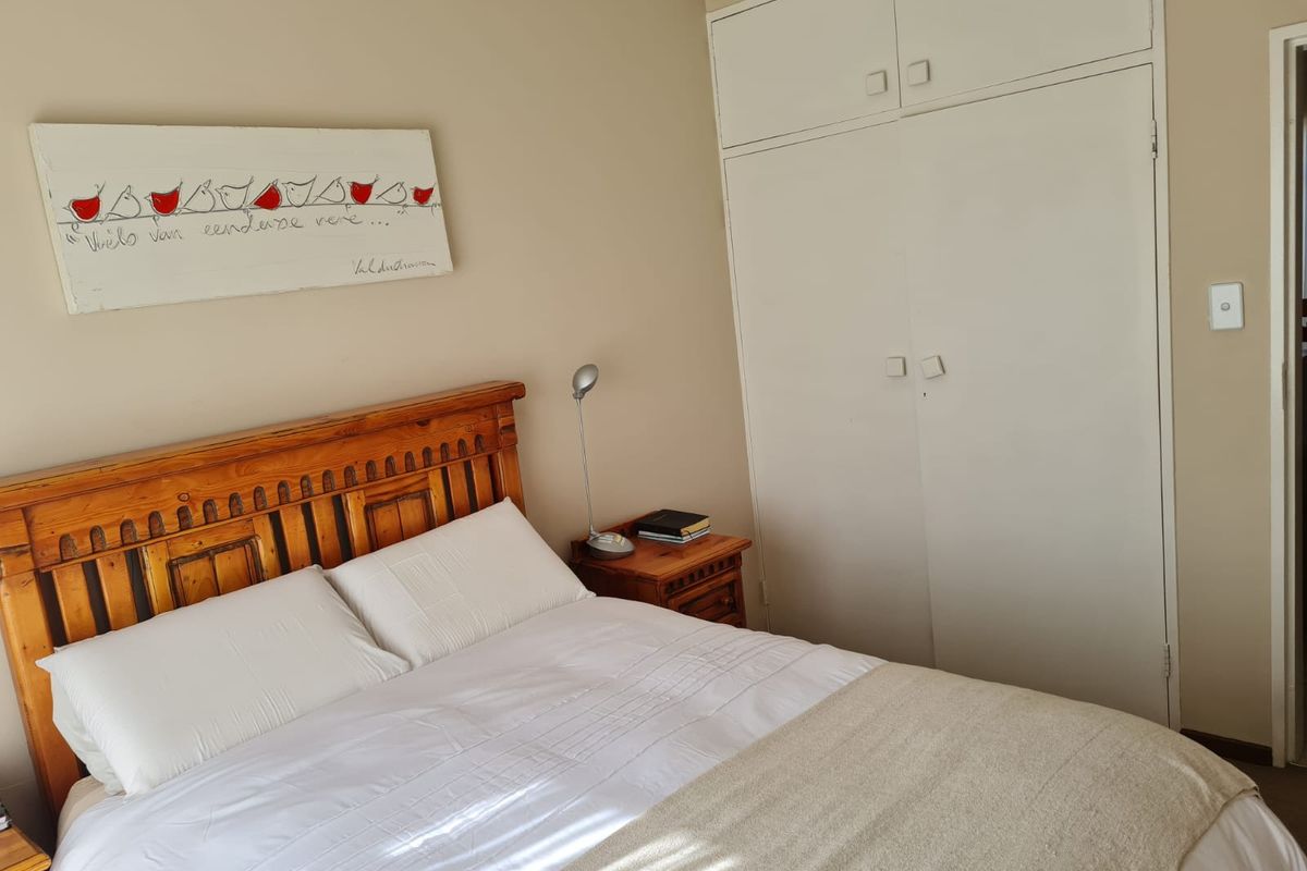 A bedroom featuring built-in cupboards with overhead storage and neutral wall finishes.