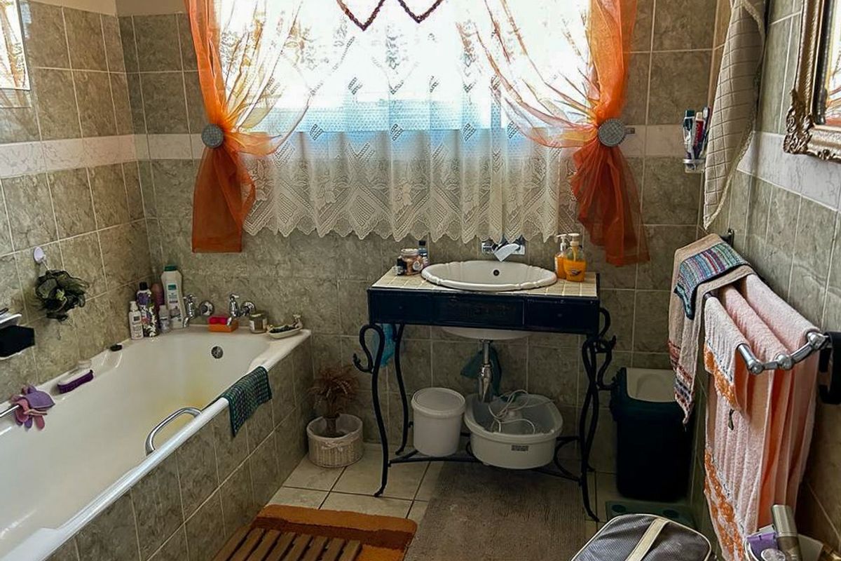 A functional bathroom featuring a built-in bathtub and a pedestal-style vanity basin with tiled wall finishes.