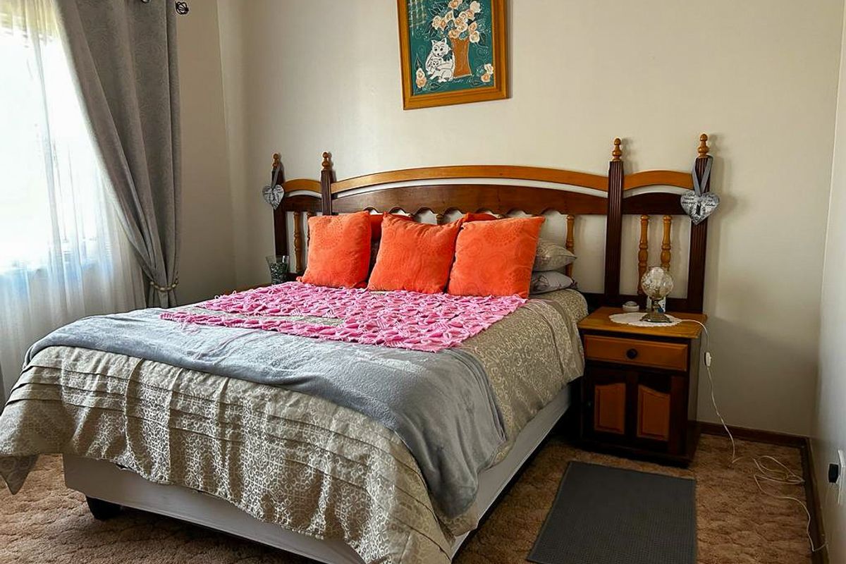 A standard bedroom featuring carpeted flooring and a window with curtain treatments.