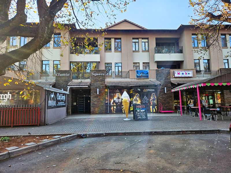 Exterior view of a multi-story apartment complex featuring ground-floor commercial retail spaces and upper-level residential balconies.