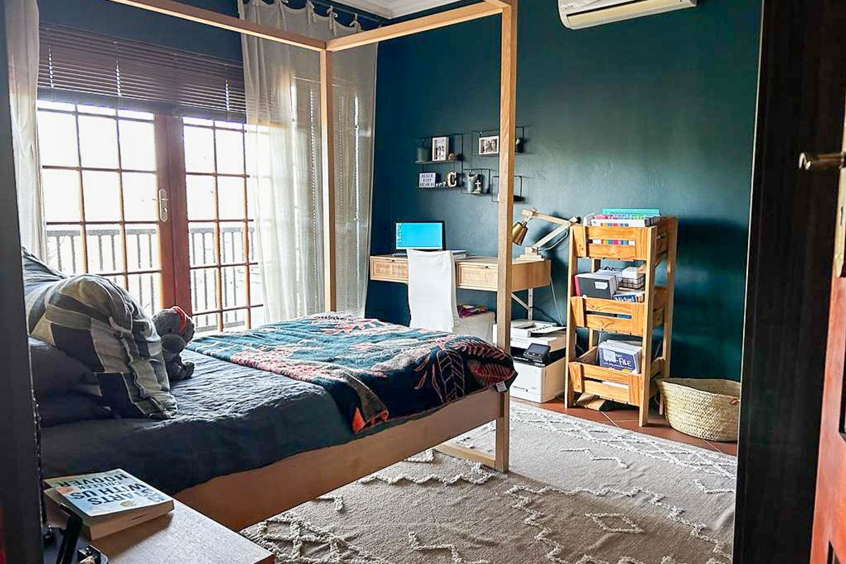 A well-maintained bedroom featuring dark accent walls, a split-system air conditioning unit, and wooden French doors leading to an outdoor area.