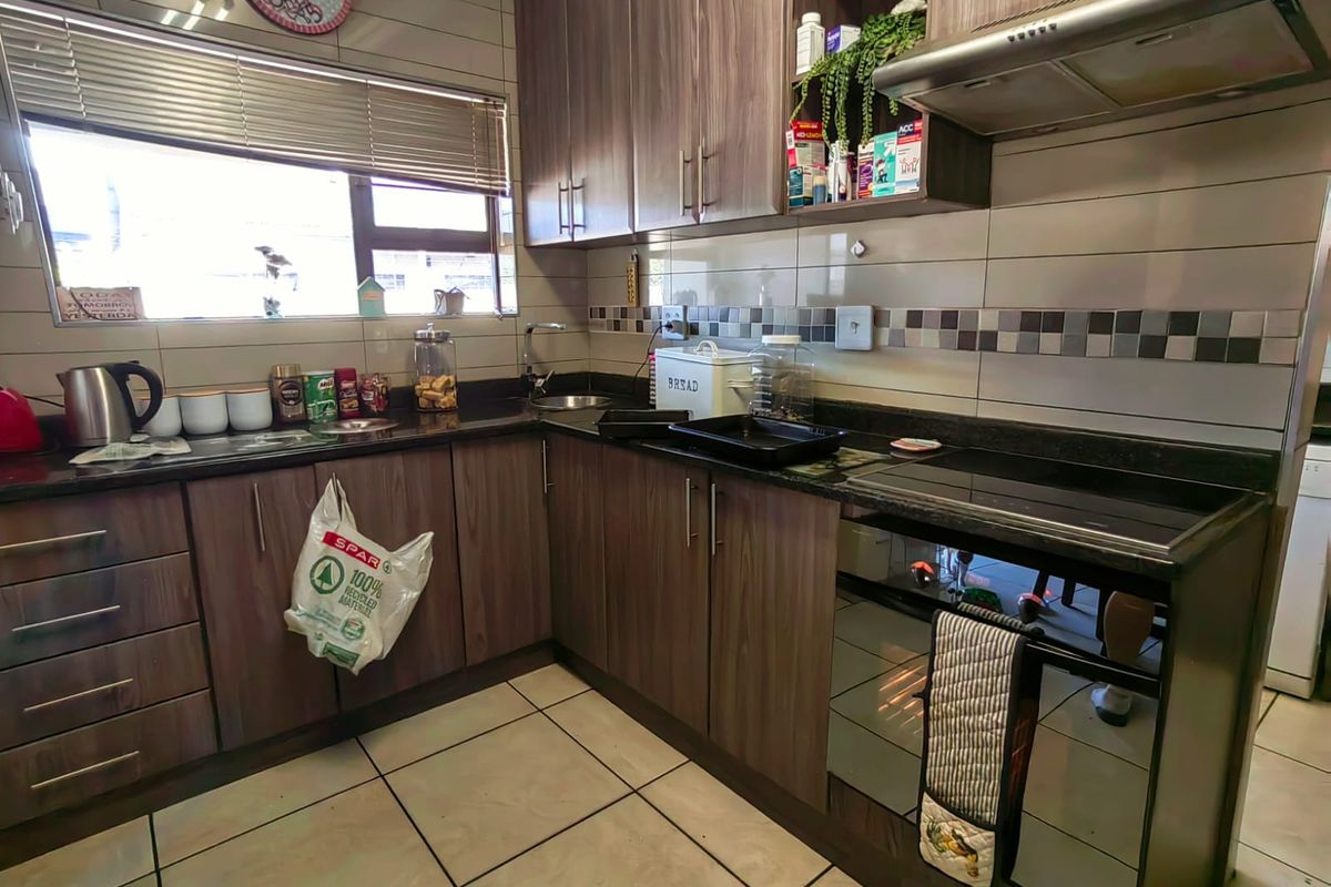 A functional kitchen featuring dark wood-look cabinetry, granite countertops, tiled backsplash, and a built-in extractor fan.