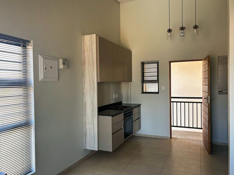 Modern kitchen area featuring sleek cabinetry, built-in oven and hob, tiled flooring, and direct access to an outdoor balcony.