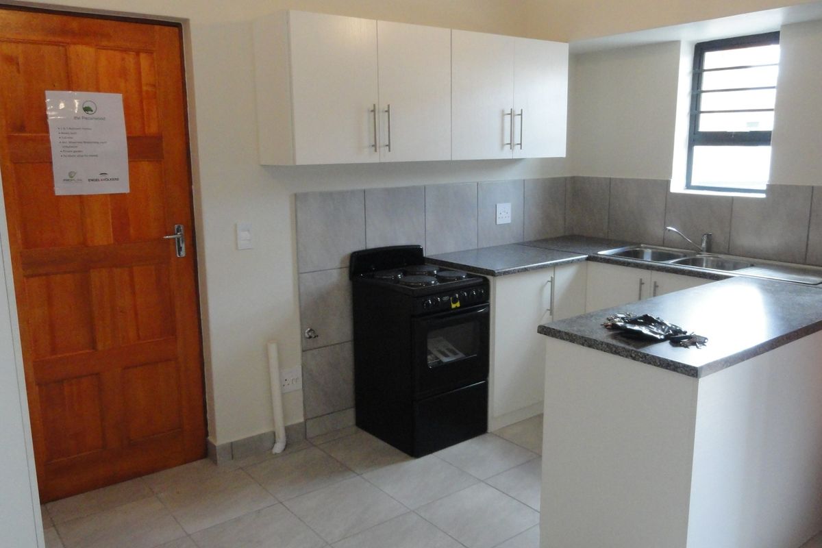 A functional kitchen featuring white cabinetry, grey countertops, tiled splashbacks, a stainless steel sink, and a freestanding electric stove.