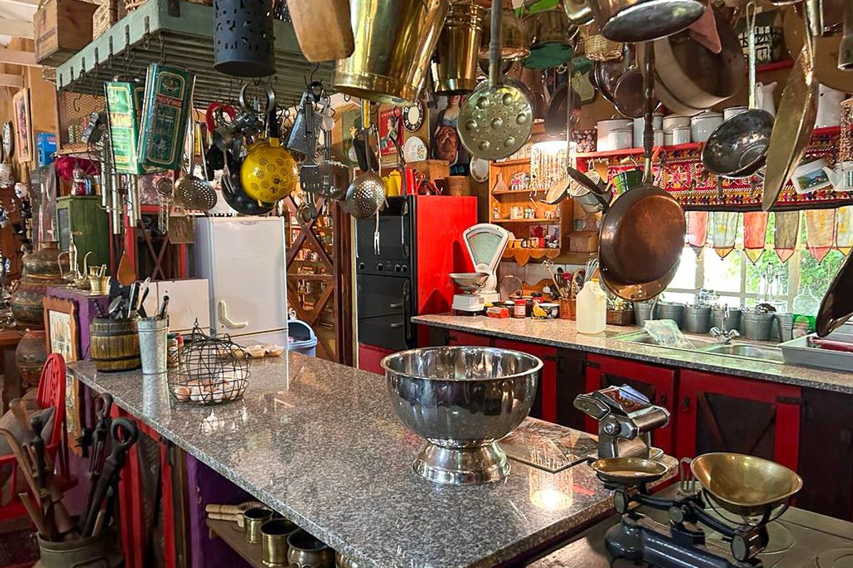 A rustic kitchen featuring granite countertops, a double sink, and extensive overhead storage racks for cookware, creating a traditional and functional culinary space.