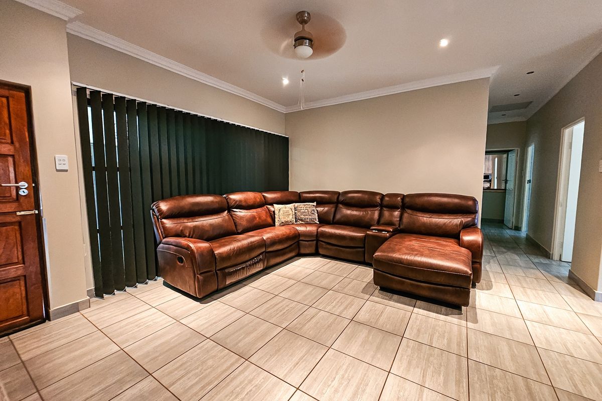 Spacious living area featuring neutral floor tiles, recessed downlighting, and a ceiling fan, providing a comfortable and functional space.