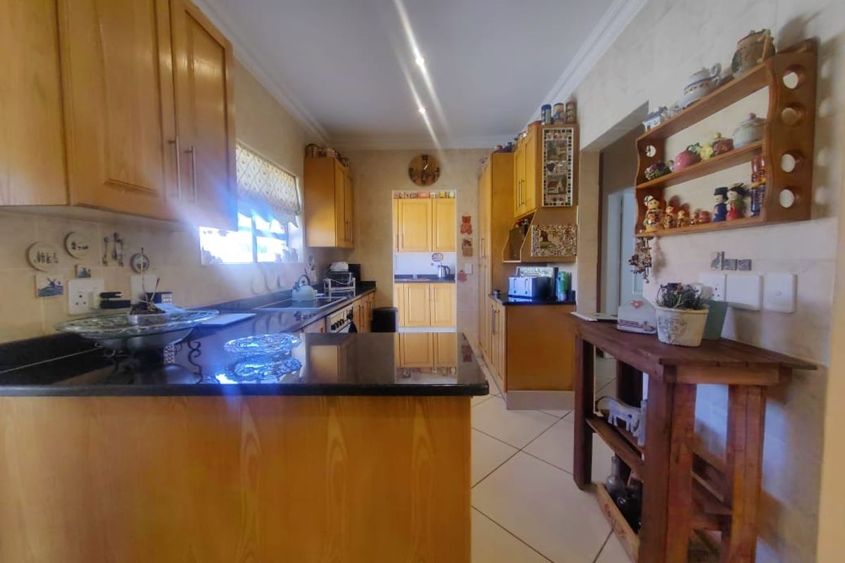 A functional kitchen featuring wooden cabinetry, dark granite countertops, and tiled flooring, with a convenient layout and direct access to an adjacent utility area.