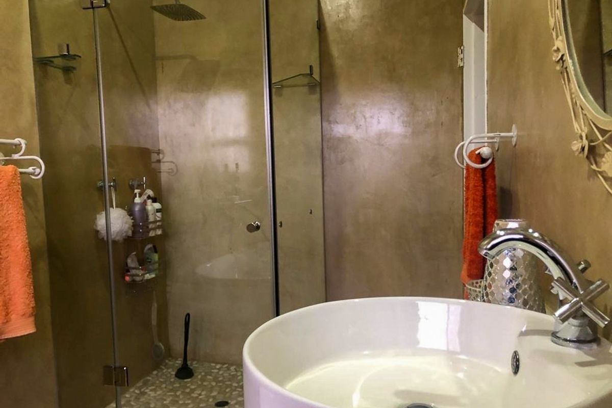 A bathroom featuring a vessel sink, chrome faucet, and a walk-in shower with a glass enclosure and pebble-style flooring.