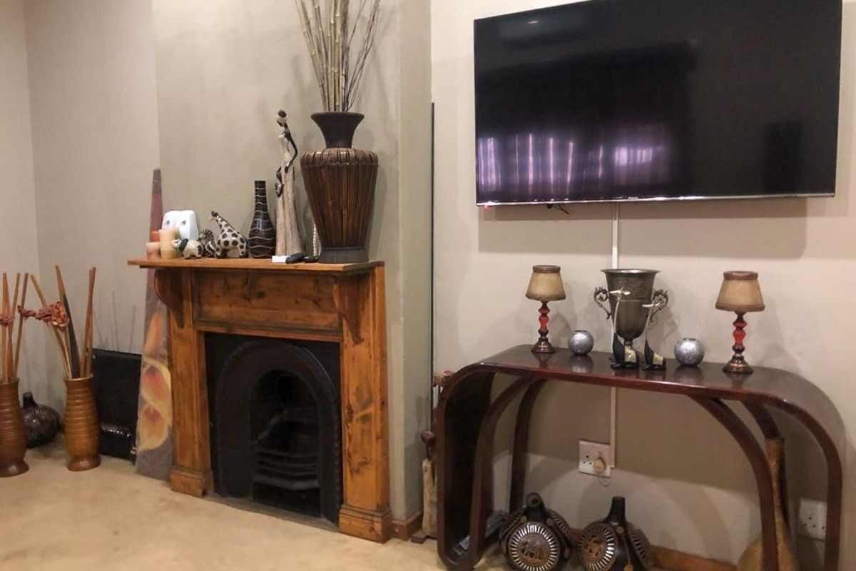 A living room featuring a traditional wooden fireplace mantel and a wall-mounted television, creating a cozy focal point for the space.