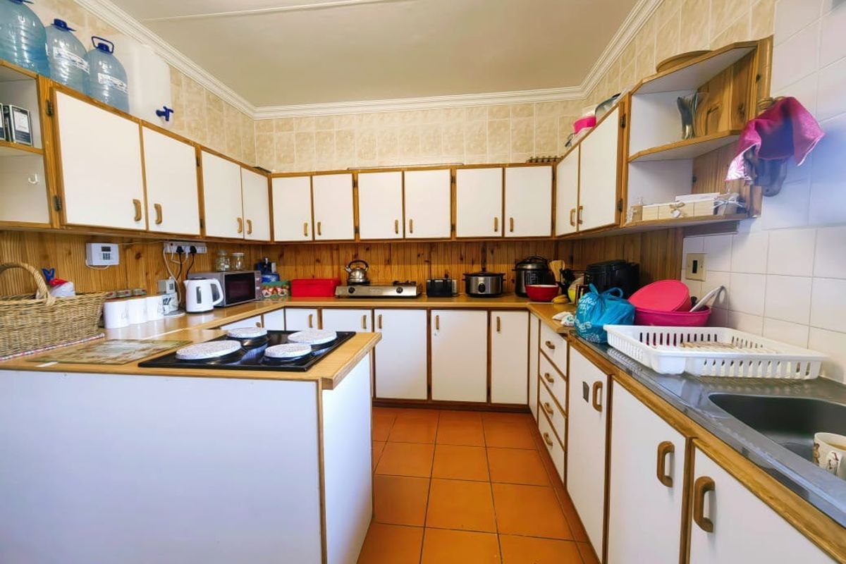 A functional U-shaped kitchen featuring white cabinetry with wood trim, a built-in hob, and tiled flooring.