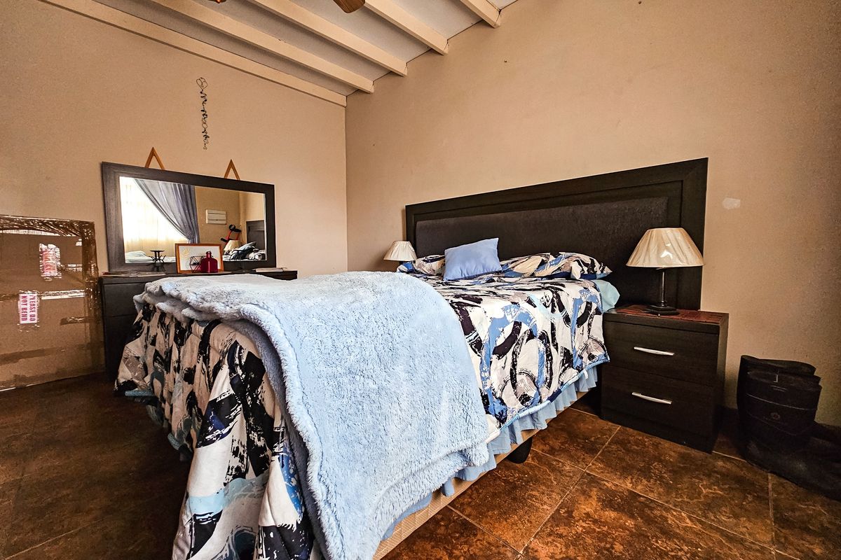 A bedroom featuring exposed timber ceiling beams and tiled flooring, providing a rustic aesthetic.