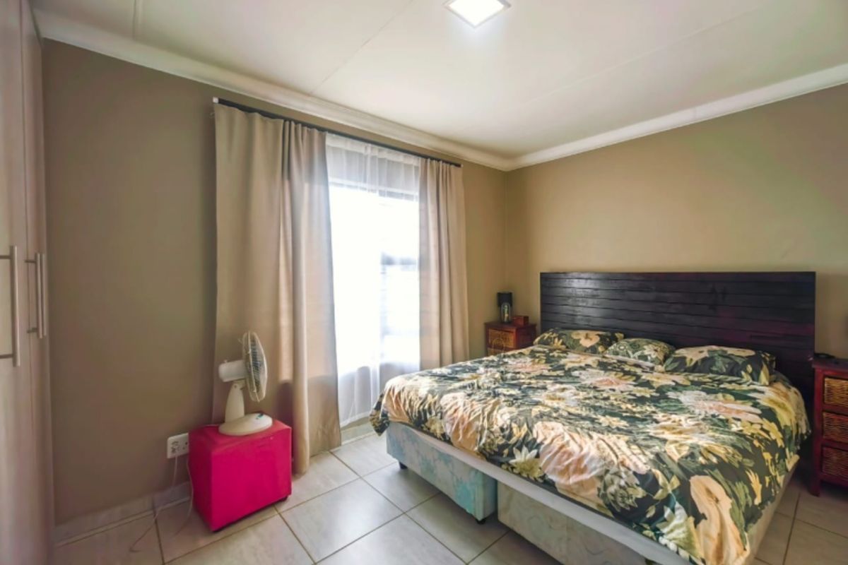 A well-lit bedroom featuring neutral wall tones, tiled flooring, and built-in cabinetry, providing a functional and comfortable living space.