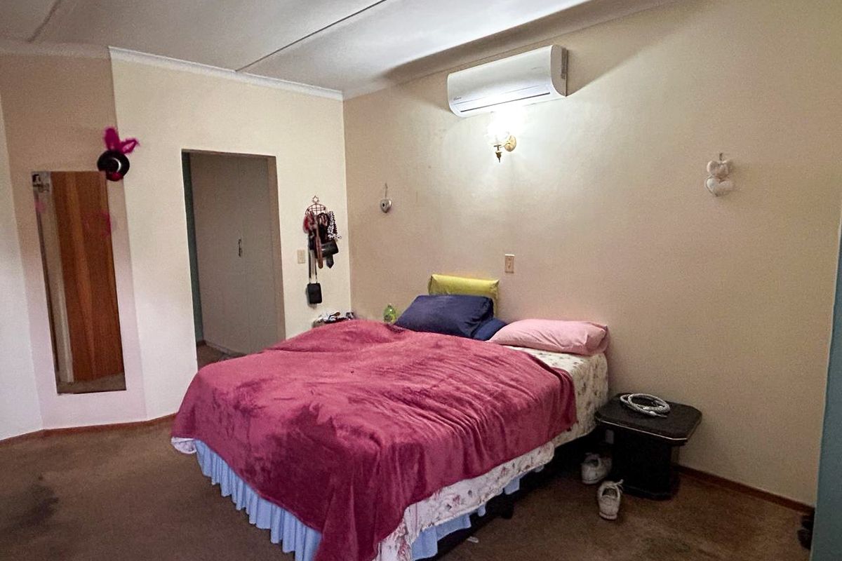 A bedroom featuring a wall-mounted air conditioning unit, carpeted flooring, and a doorway leading to an adjacent space.
