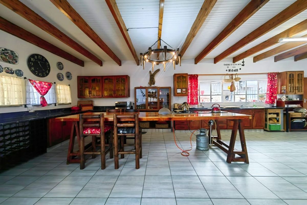 Spacious kitchen featuring exposed timber ceiling beams, wooden cabinetry, a large central island, and tiled flooring throughout.
