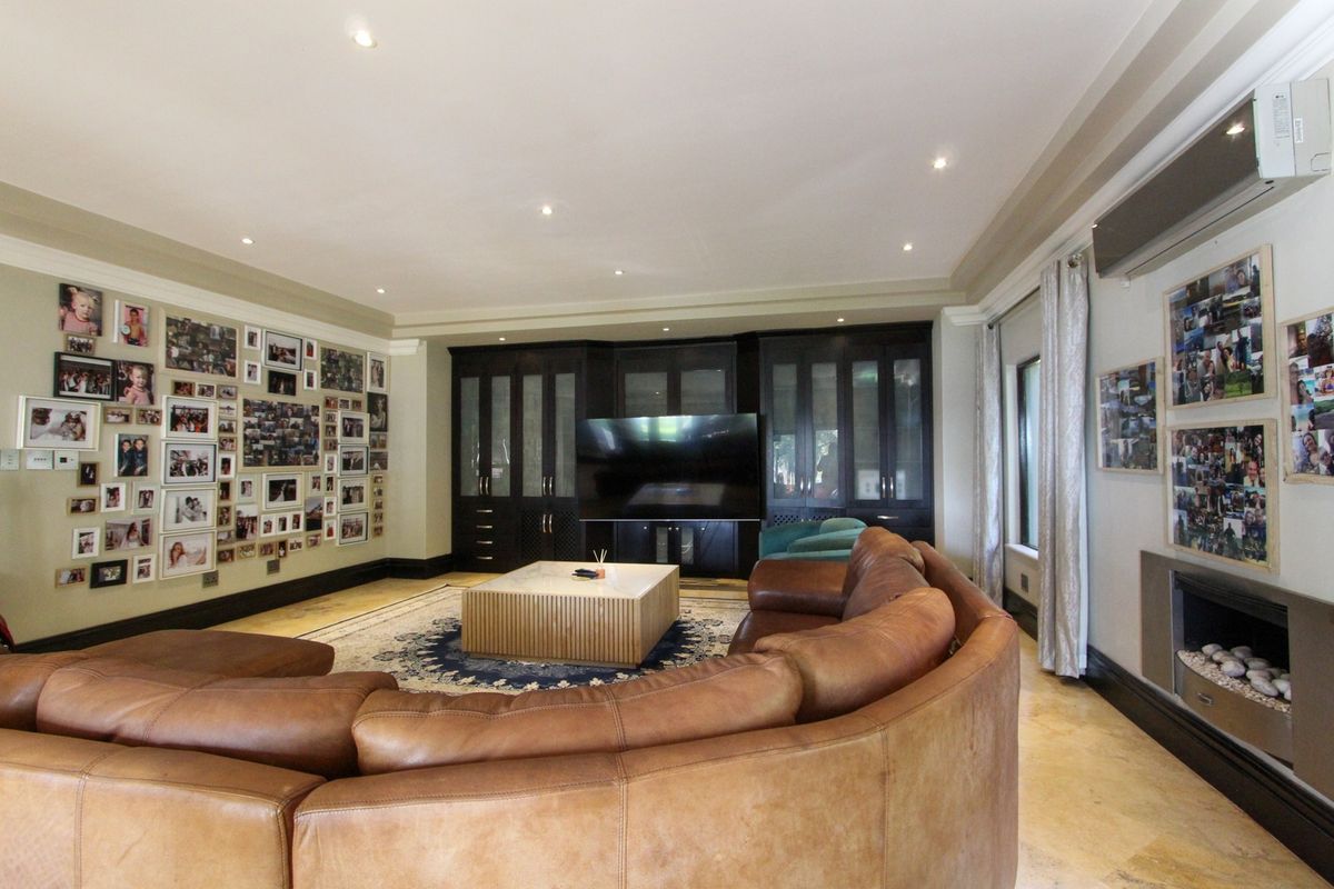 Spacious living room featuring built-in dark wood cabinetry, a modern fireplace, recessed lighting, and polished stone flooring.
