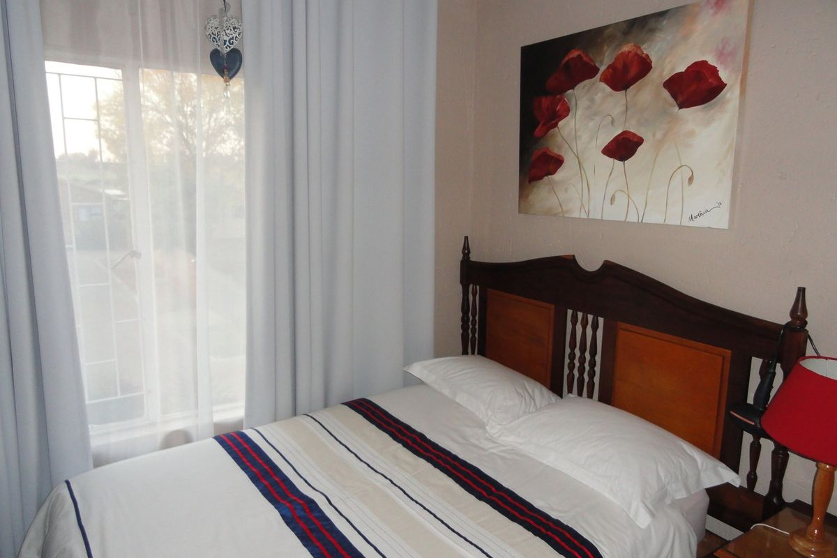 A cozy bedroom featuring a window with security bars and neutral wall finishes.