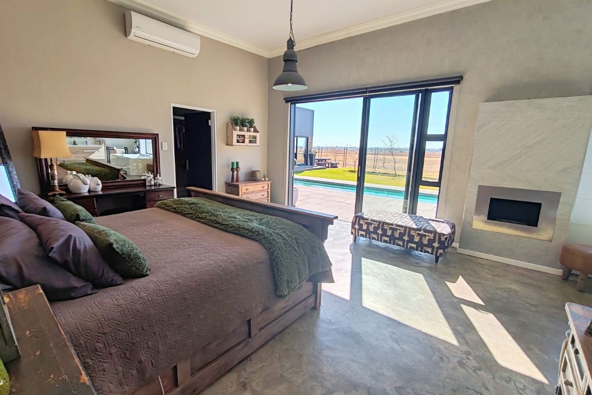 Spacious bedroom featuring polished concrete floors, a built-in fireplace, and large sliding glass doors opening to a private pool area.