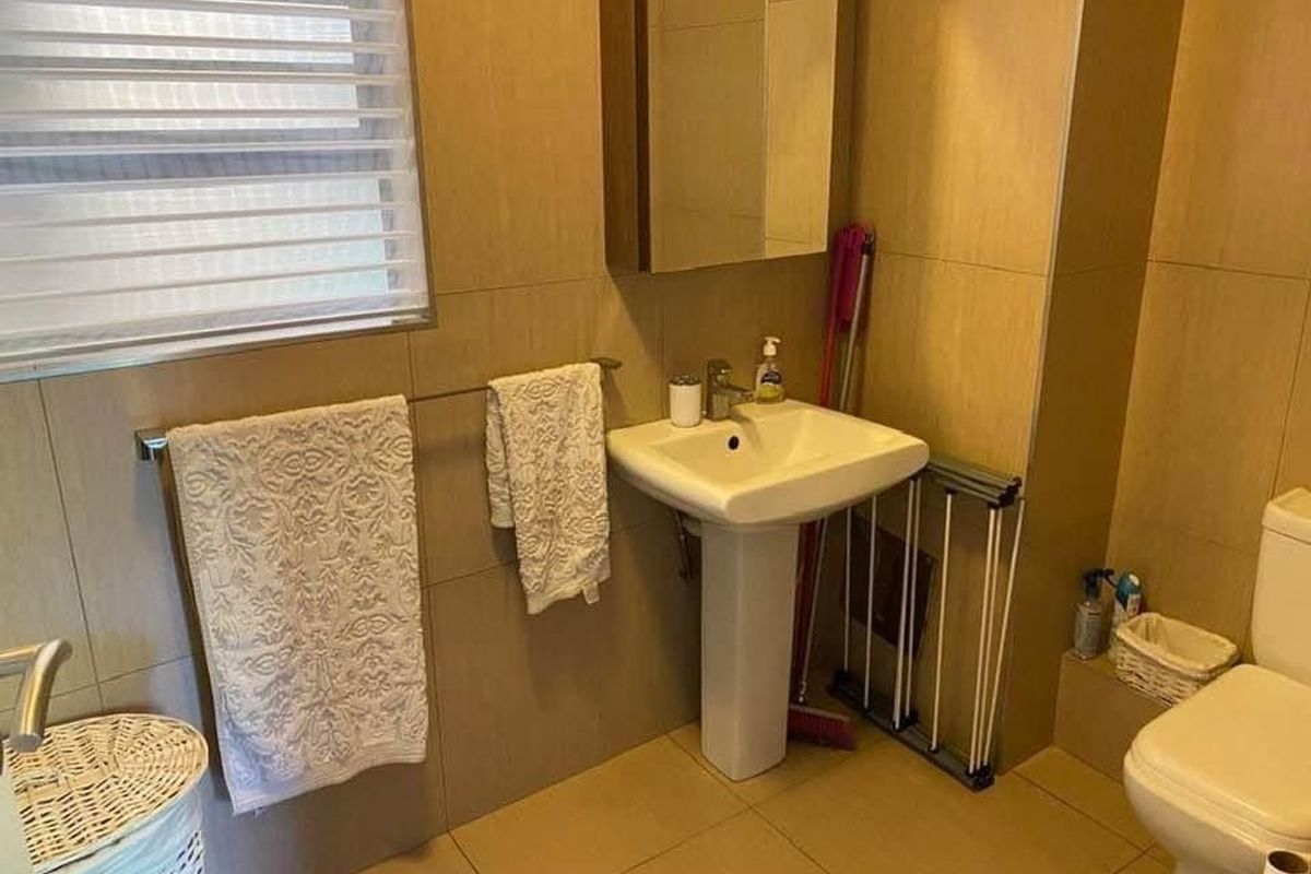 A functional bathroom featuring a pedestal sink, wall-mounted medicine cabinet, and neutral floor-to-ceiling tiling.