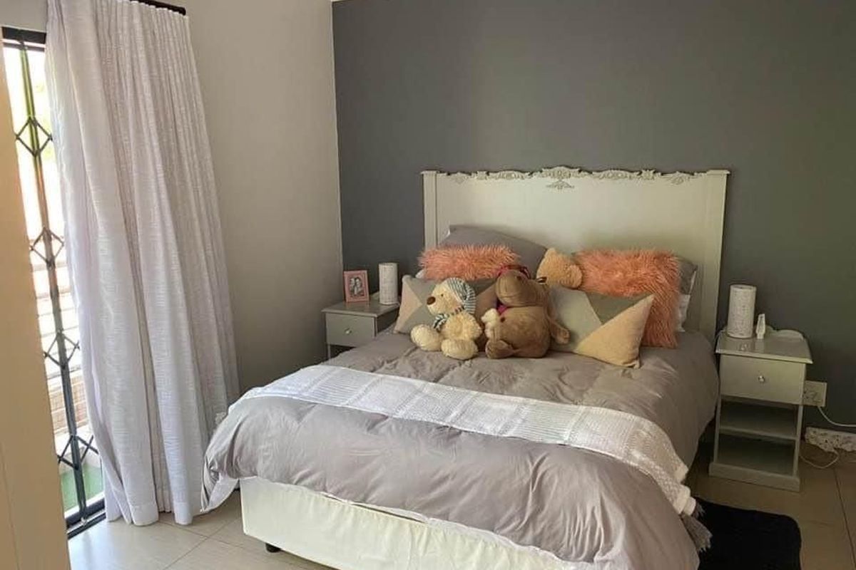 A well-maintained bedroom featuring neutral tiled flooring, a dark grey accent wall, and a sliding door providing access to an outdoor area.