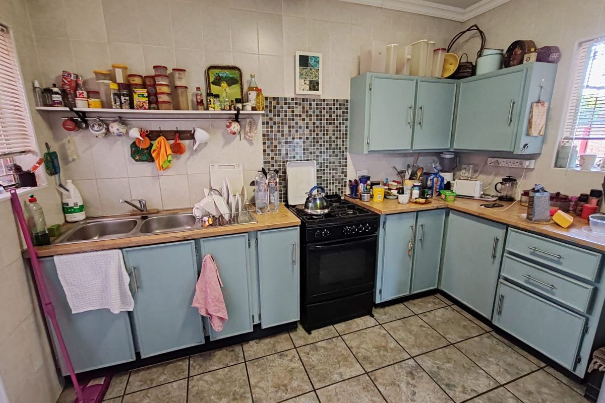 A functional kitchen featuring light blue cabinetry, wood-look countertops, a built-in gas stove, and tiled flooring with a mosaic tile backsplash.