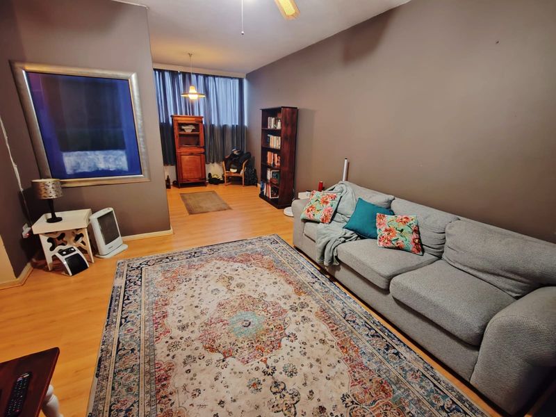 A living room featuring laminate flooring, neutral wall paint, and a ceiling fan, providing a comfortable and functional living space.