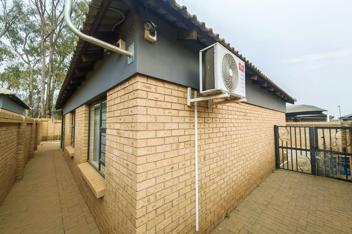 Side exterior view of the townhouse featuring face-brick walls, tiled roof, and a wall-mounted air conditioning unit.