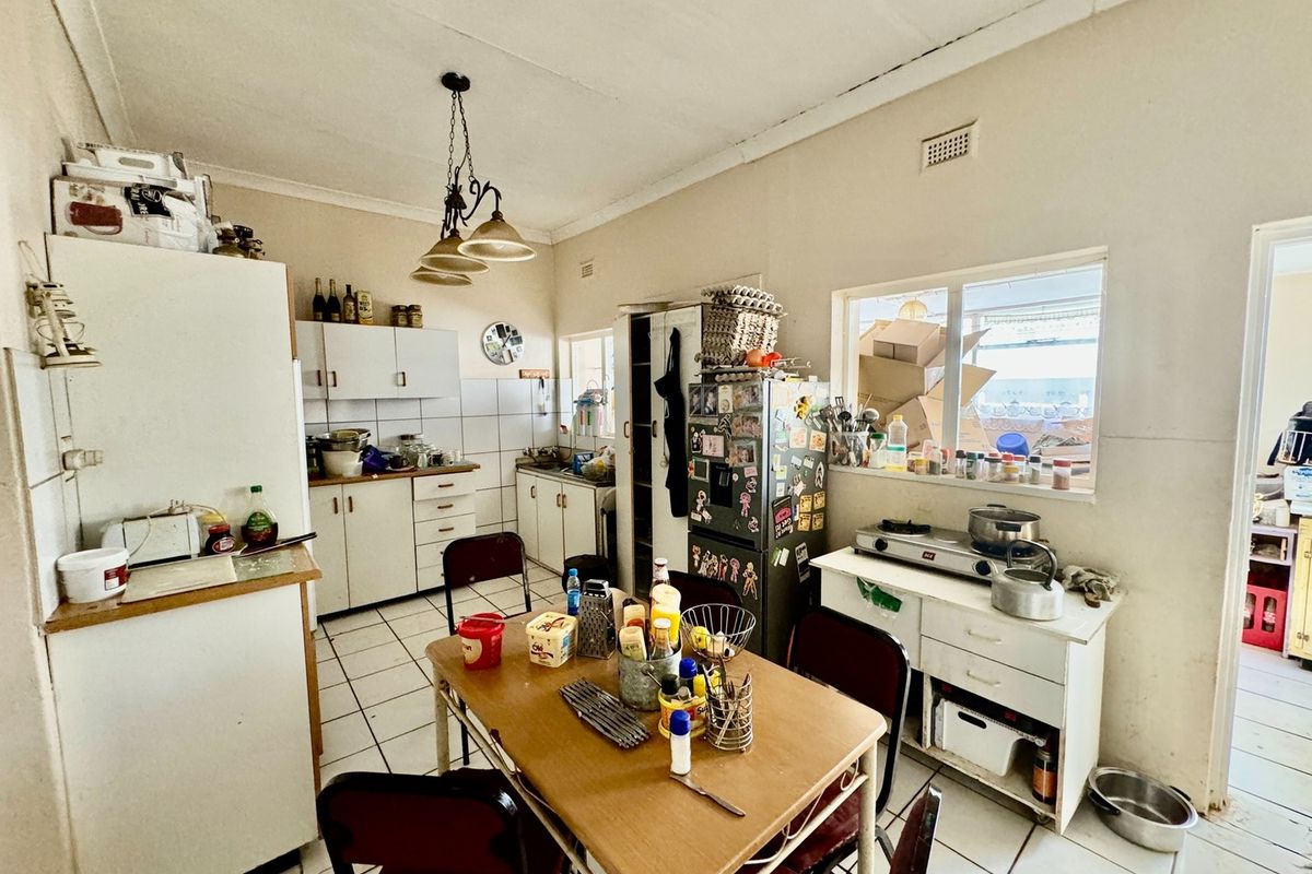 A functional kitchen space featuring tiled flooring, built-in cabinetry, and a central dining area, offering potential for modernization and renovation.
