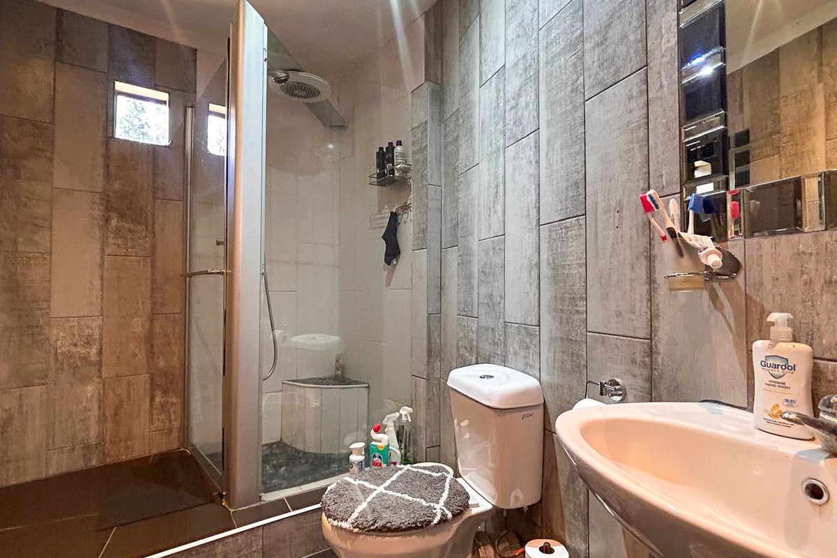 Modern bathroom featuring a glass-enclosed shower, contemporary grey wall tiling, a pedestal basin, and a standard toilet.