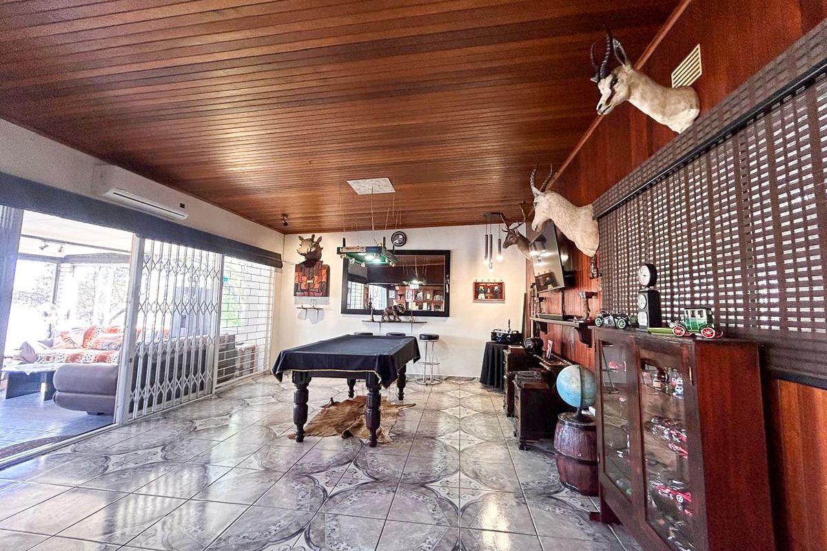 Spacious entertainment room featuring a wood-paneled ceiling, tiled flooring, and sliding glass doors leading to an outdoor patio area.