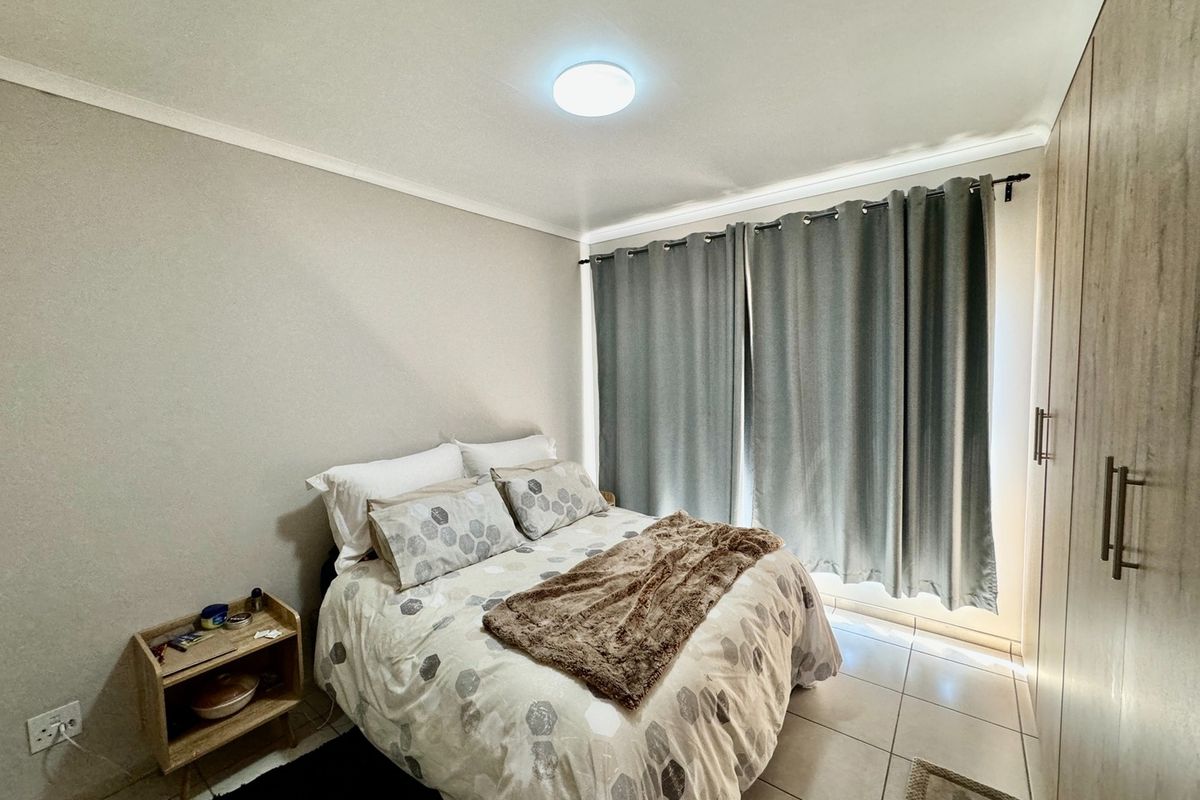 A well-maintained bedroom featuring built-in wooden cupboards, tiled flooring, and neutral wall finishes, providing a clean and functional living space.